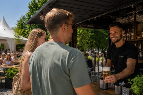 Außengastronomie Ideen: Kellner reicht Gästen ein Bier rüber