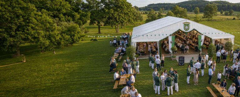 Checkliste Schützenevent planen: Eventzelt auf einer großen Wiese, umgeben von Leuten.