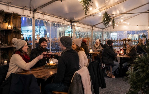 Ideen Weihnachtsmarkt: Freundesgruppe sitze am Tisch und stoßt an